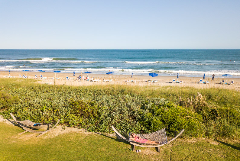 blockade-runner-beach-resort-wrightsville-beach-nc (1) aerial of woman on hammock on grassy area in front of Wrightsville Beach NC