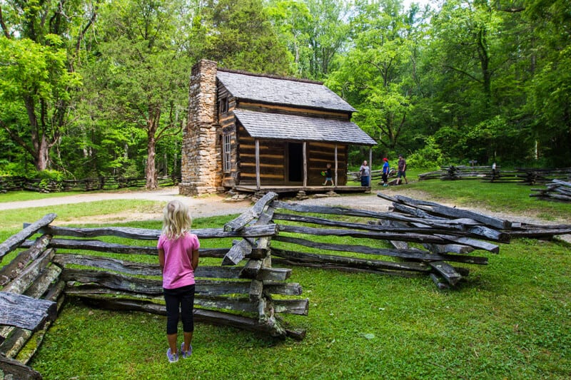 Cades Cove bike ride Smoky Mountains National Park (7) young girl looking at wood cabin on Cades Cove Loop Road