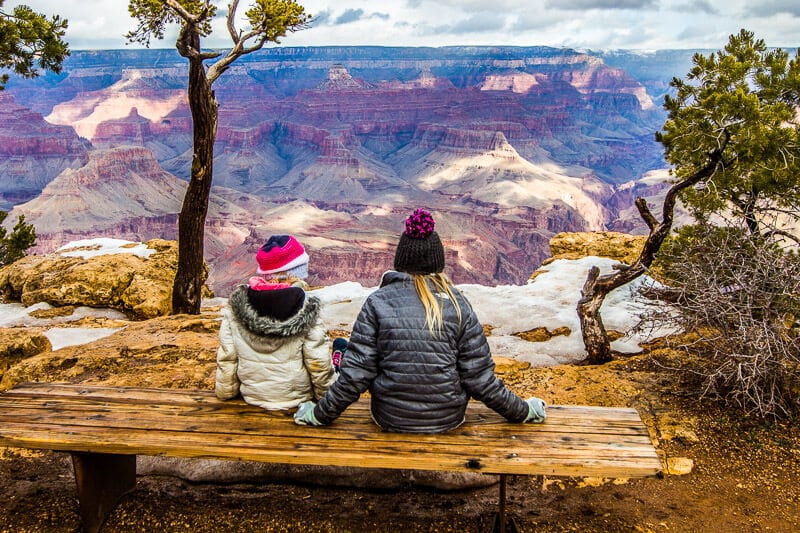 grand canyon with kids two girls sitting on bench looking at grand canyon views.