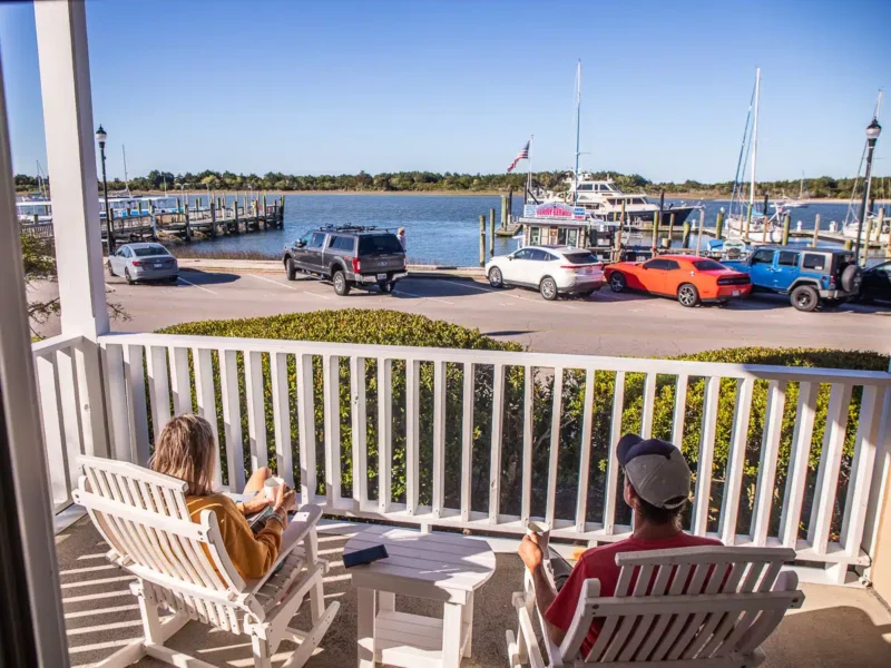 man and woman on balcony having morning coffee with water views