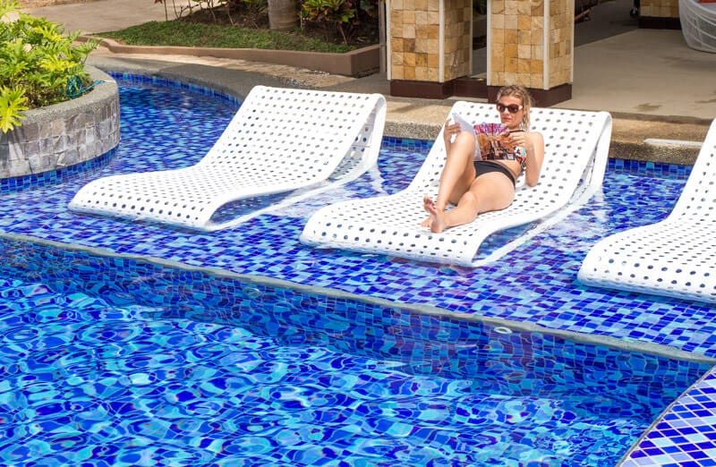 movenpick-boracay-island-philippines-11 woman sitting on a lounge chair next to a pool