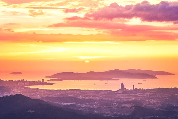 View of silhouette landscape with Kota Kinabalu city against islands at golden sunset. Sabah state, Malaysia.