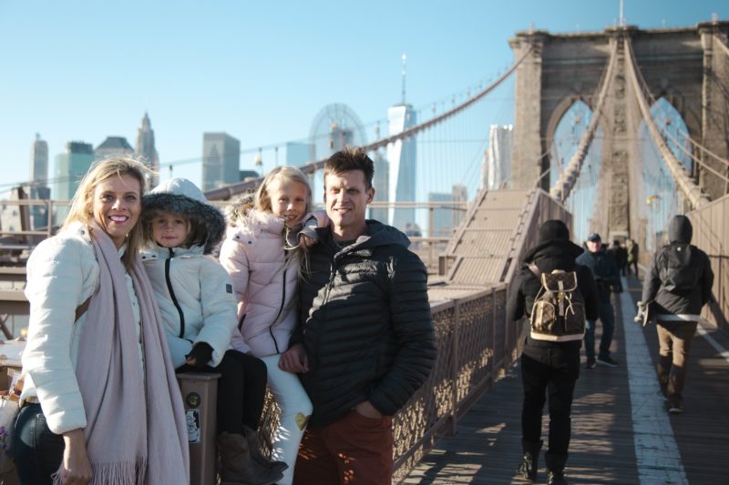 Wanderloud / Book a local photographer and travel unplugged fmaily posing on brooklyn bridge with NYC skyline in background